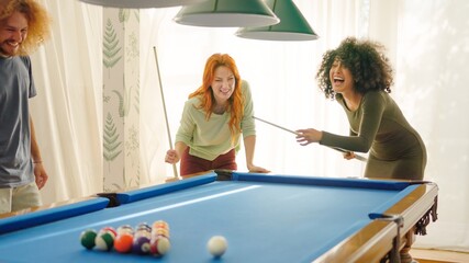 Friends laughing when woman playing awful at pool