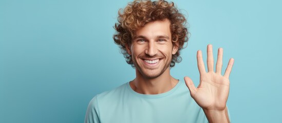 Man with curly hair wearing a blue shirt is gesturing with his hand to make a stop sign