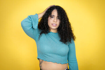 African american woman wearing casual sweater over yellow background putting one hand on her head...