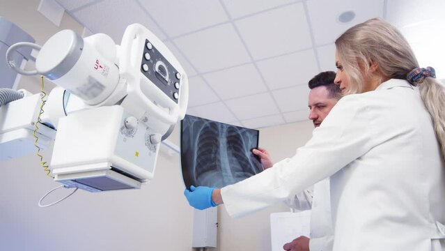 Specialists consult in the X-ray room. Lung diseases, inflammation and colds after Covid. Medical coaching and collaboration to achieve patient outcomes.