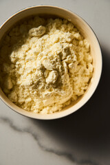 Dry powdered milk. Dehydrated Milk powder in the bowl on white marble background, Minimalistic food photo.