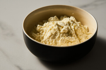 Dry powdered milk. Dehydrated Milk powder in the bowl on white marble background, Minimalistic food photo.