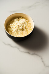 Dry powdered milk. Dehydrated Milk powder in the bowl on white marble background, Minimalistic food photo.