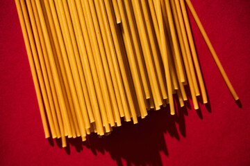 Bucatini raw pasta macaroni background on vibrant and contrast red backgrorund. Hard light,...