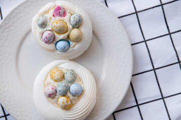 Pavlova dessert with sweet Easter Eggs. An interesting meringue dessert for the Easter table - obrazy, fototapety, plakaty