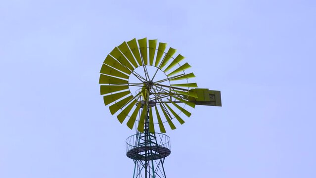 Yellow windmill with green base and blue background