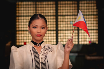 A tour guide wearing a baro't saya showcases culture inside a historical Filipino house while holding the Philippine Flag.