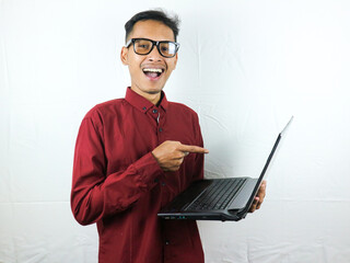 portrait of an asian man wearing a red clothes holding a laptop with a smiling face expression.