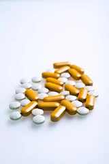Foto auf Glas Witte en oranje pillen of supplementen ter verbetering van de gezondheid, tegen een witte achtergrond. © ArieStormFotografie