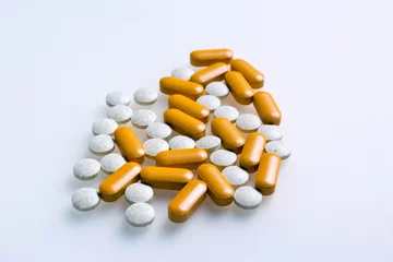 Fototapeten Witte en oranje pillen of supplementen ter verbetering van de gezondheid, tegen een witte achtergrond. © ArieStormFotografie