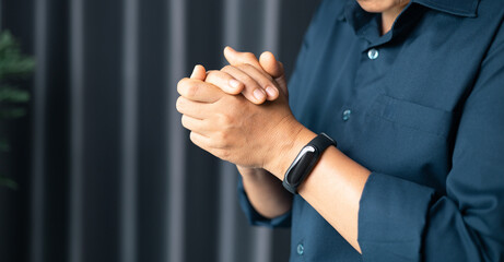 Woman with hands clasped praying while sitting at desk in office. Businesswoman praying at work. Contemplative prayer thinking in office. Hands folded in prayer gesture beg about something.