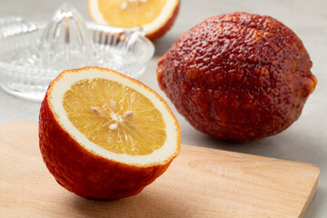 Whole and halved fresh Citrus limon Rosso, Red lemon, close up on a cutting board 