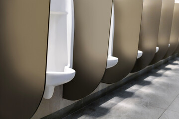 Modern white ceramic urinals for man in public toilet room.