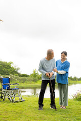 Fototapeta premium Asian nurse caring for an old man in the garden at home, nurse caregiver supporting health insurance at home or hospital, elderly man