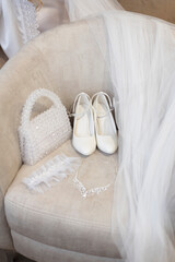 Fototapeta na wymiar Bride's shoes, handbag and veil on a chair