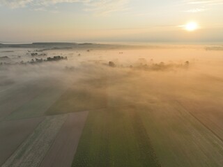 Brzask na wsi z lotu ptaka, ujęcia z drona wsi o brzasku, wschód słońca na wsi, pusząca się o poranku wieś, pola owite mgłą o brzasku, poranek we mgle © klumb