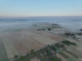 Brzask na wsi z lotu ptaka, ujęcia z drona wsi o brzasku, wschód słońca na wsi, pusząca się o poranku wieś, pola owite mgłą o brzasku, poranek we mgle © klumb