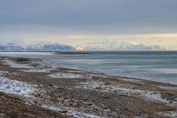 Winter seascape. View of the icy seashore. Mountains in the distance. Cold frosty winter weather. Sea of Okhotsk, Magadan region, Russian Far East.