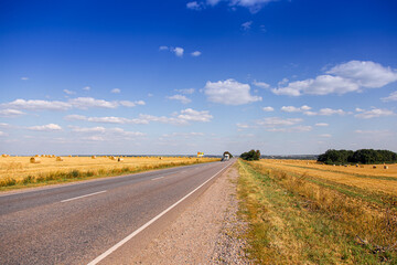 The road among the fields on a bright autumn day. Cereal fields. Rural landscape