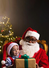 Fototapeta na wymiar Santa Claus with a child on his lap and a small present.