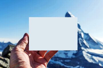 Hand Presenting White Card with Snowy Mountain Peak in Background, Clear Blue Sky, Daytime - Powered by Adobe
