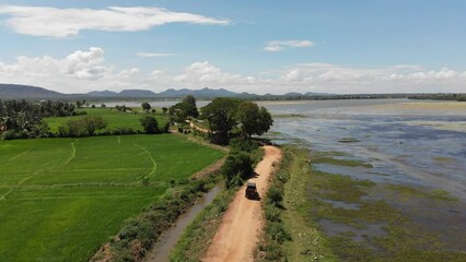The Vehicle ventures down the village road, Dust clouds billow behind as it draws the attention of villagers, a familiar sight in the serene countryside. 