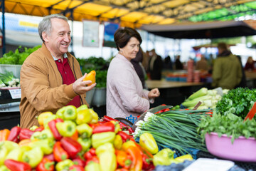Elderly men and women buying peppers at an open market