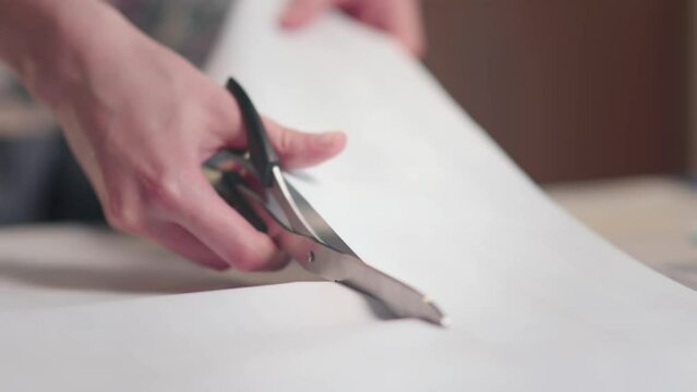 Workplace of seamstress. Close up dressmaker cuts dress detail with scissors