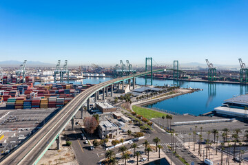 Aerial view of the Vincent Thomas Bridge. Port with cranes and several colorful containers. Sunny day. San Pedro, CA, USA