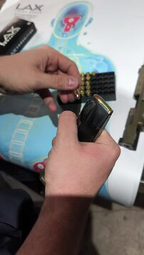 gros plan sur les mains du personne remplissant de balles, un chargeur de pistolet 