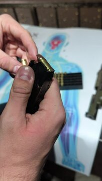 gros plan sur les mains du personne remplissant de balles, un chargeur de pistolet 