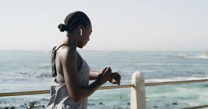 Fitness, beach or black woman with smart watch to monitor workout, exercise or training performance. Start, music earphones or sports athlete checking timer for heart rate, pulse or running progress