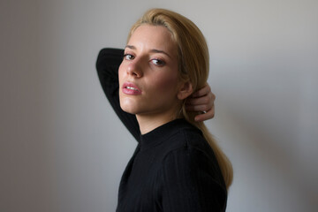 Fototapeta premium Close up photo of a beautiful caucasian blonde woman with bun on her head looking at camera. 