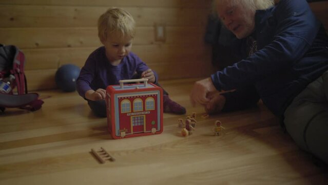 Lockdown Shot Of Grandfather Playing With Grandson On Hardwood Floor In Playroom At Home - Fairbanks, Alaska