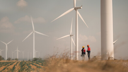 Young man and woman maintenance engineer team. two engineer operate wind turbine. Engineer and worker discussing on a wind turbine farm. Wind Turbine. Maintenance Workers. renewable energies.. - obrazy, fototapety, plakaty