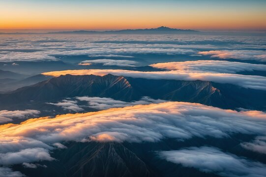 Aerial view of mountain range surrounded by low clouds at sunset as seen from the plane