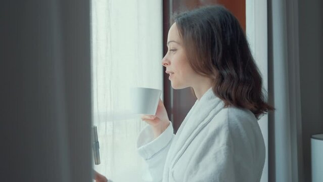 Smiling Woman Holding a Cup by Window