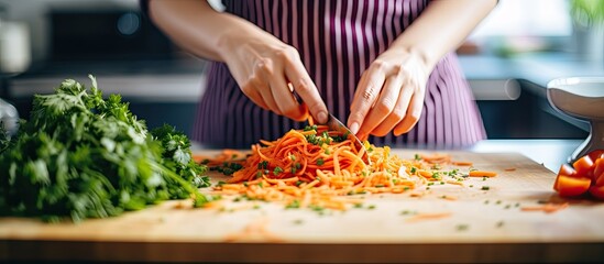 A person is slicing various vegetables on a wooden chopping board with a sharp knife, preparing a healthy meal