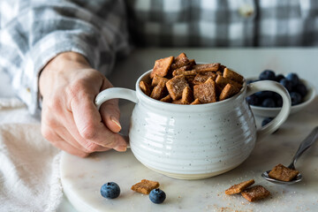 A bowl of low carb cinnamon toast crunchy cereal with blueberries.