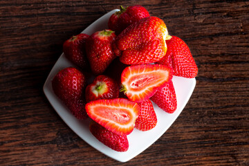 Strawberries on a white plate and wooden background.