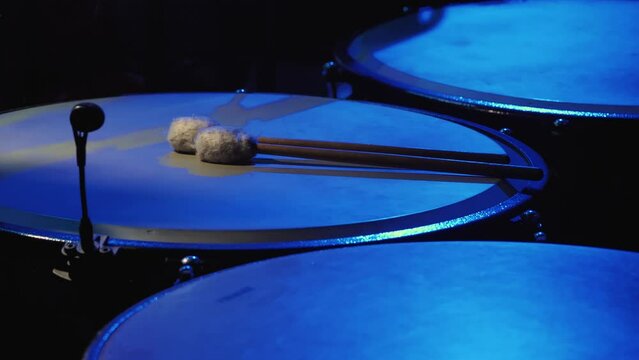 Close-up of the head of blue tam-tam drums. On the drums there are sticks with soft tips. The instruments are used in a symphony show