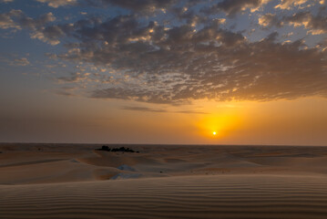 Beautiful dramatic clouds sunset sunrise over the desert sand dune of Abu Dhabi