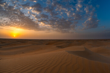 Beautiful dramatic clouds sunset sunrise over the desert sand dune of Abu Dhabi