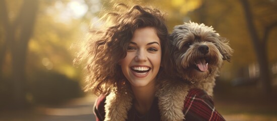 The woman is smiling while holding a toy dog on her shoulder at a happy event. The dogs fur looks fluffy and they seem to be having fun on the grass. The companion dog is a great travel companion