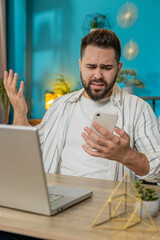 Caucasian young businessman using smartphone typing browsing loses becoming surprised sudden...