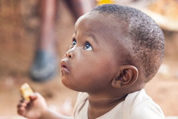 village hungry african boy eating some cheap biscuits, in the yard