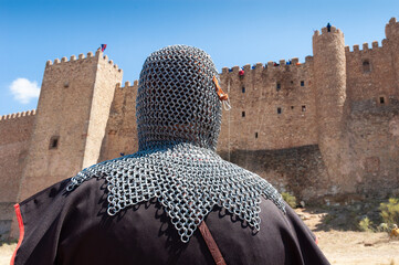 Un caballero medieval con cota de malla observa el asalto a las murallas del castillo durante un festival medieval.