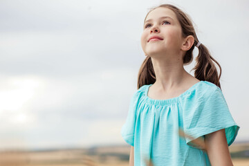 Portrait of adorable girl looking up against sky background