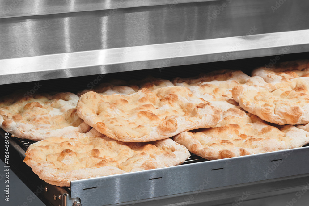 Poster fresh fragrant flatbread bread on a metal table in a bakery. nutrition concept