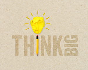 Yellow paper light bulb metaphor for creative and think big with pencil on brown recycled background